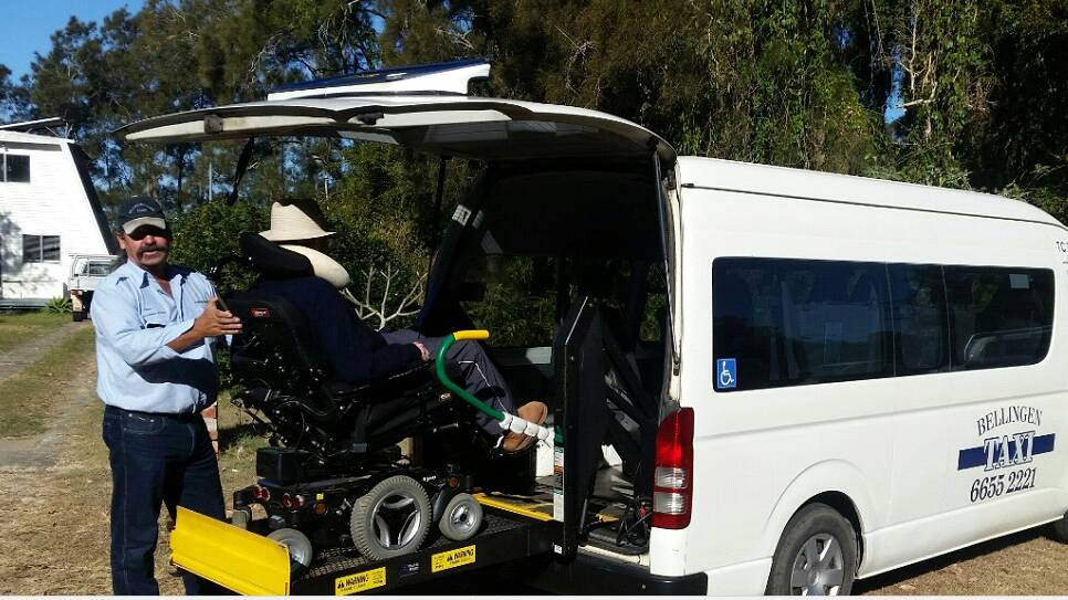 Greg McLeod placing local Ken Weekes in the wheelchair taxi at the soccer semi-finals in Urunga