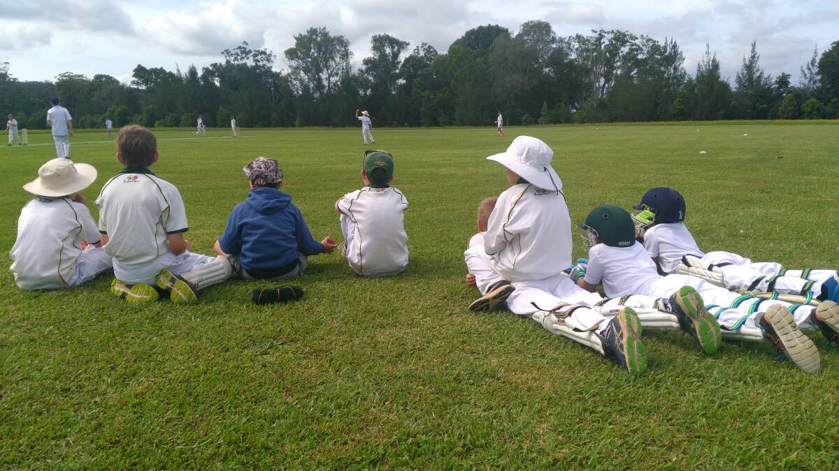 An early season game - the Dorrigo team watching from the sidelines at Nana Glen Cricket Ground