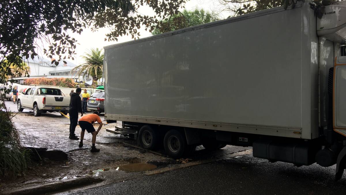 It took a community effort to free this delivery truck when it was stranded in deep potholes on Friday. Photo Megan Gale