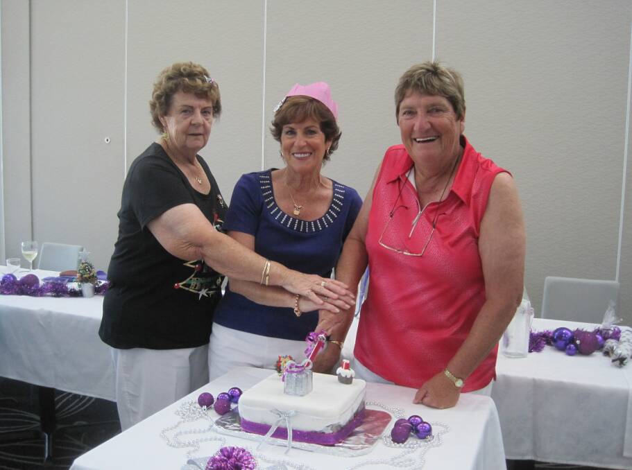 Cutting the yummy Christmas cake (made by VP Pat) are Margaret Baldwin, Pat Herrmann and President Shirley Willis.