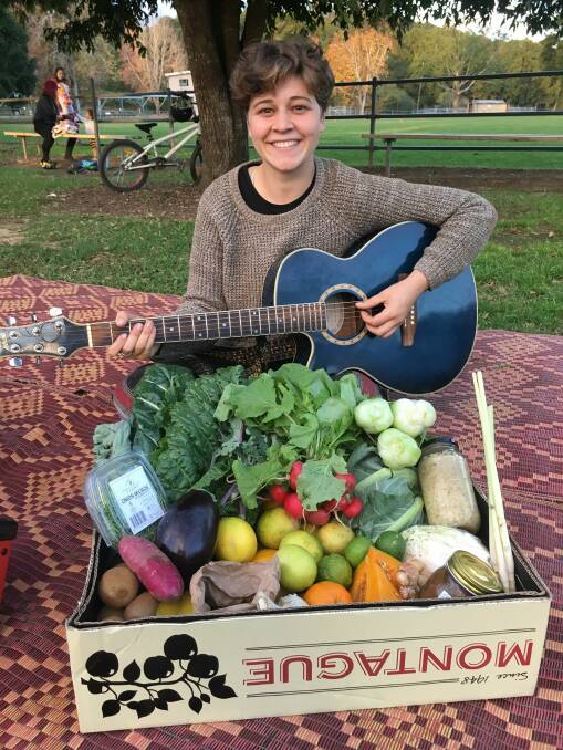 Hannah Harlen, local musician and her abundant box of produce for busking at the market

