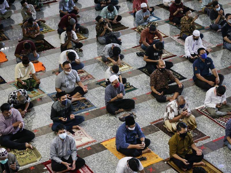 Muslims have held communal Friday prayers at reopened mosques at half capacity in Jakarta.